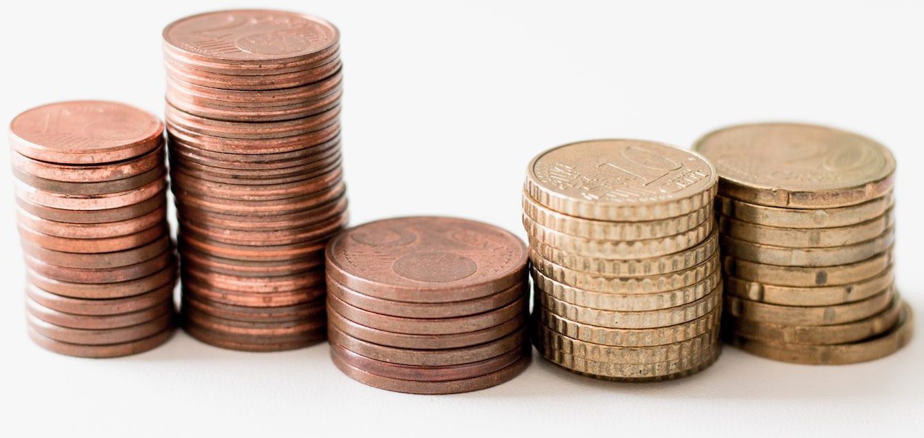 stacked round gold-colored coins on white surface